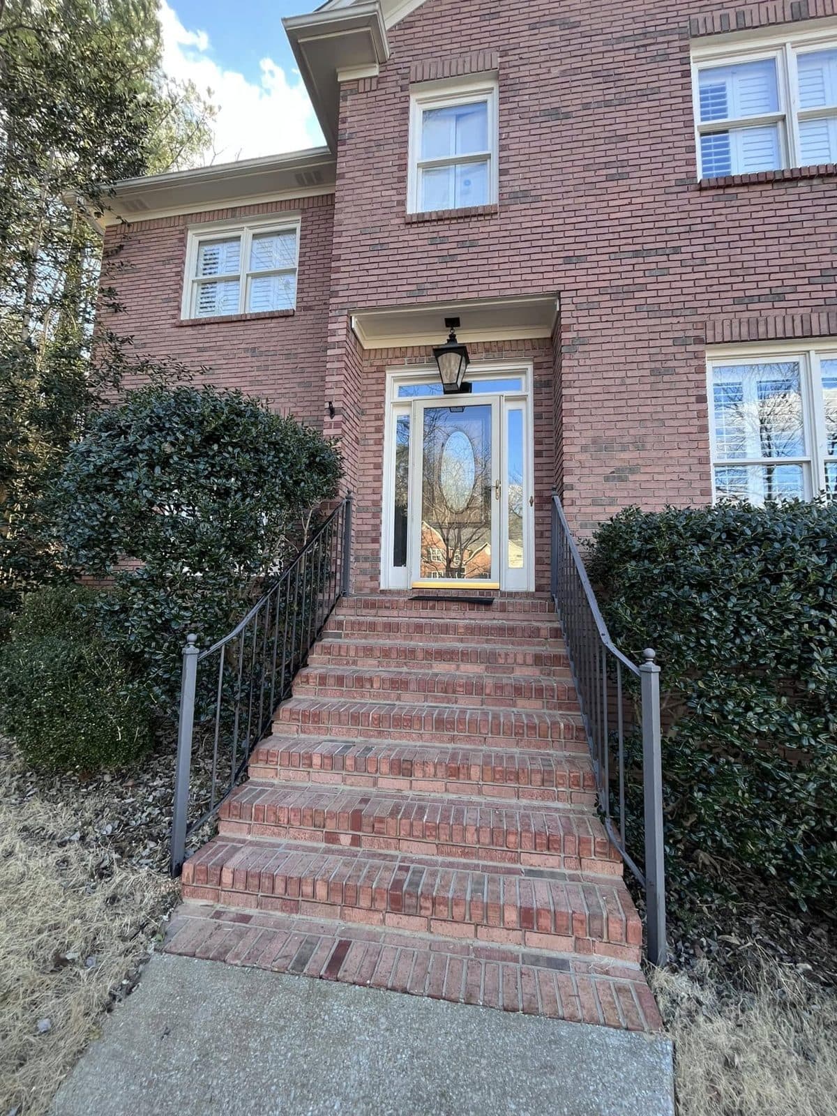 Red brick two story home, front steps and iron rails after a house wash, Birmingham metro