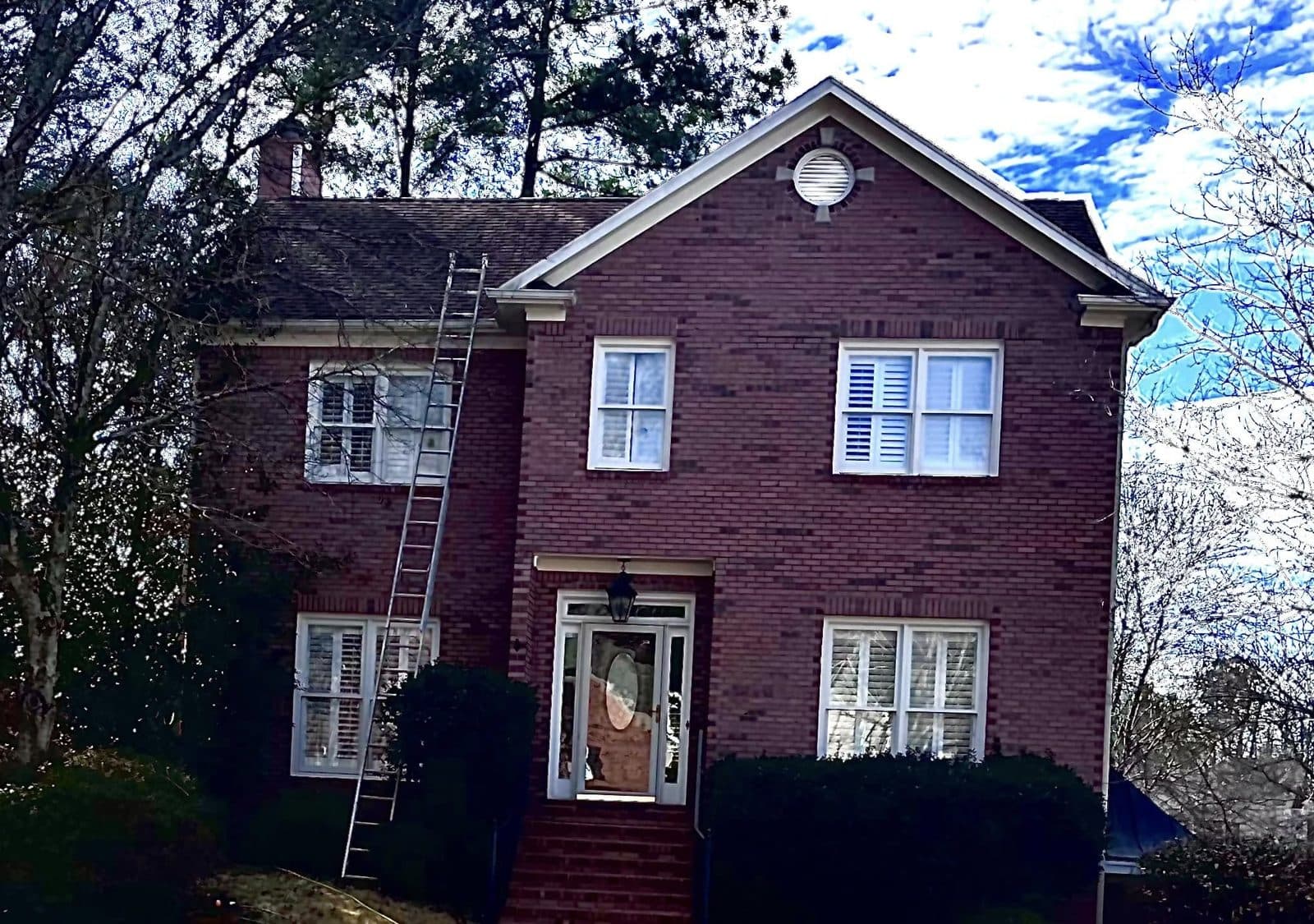 Ladder up against a red brick two story home during a roof wash, Birmingham metro